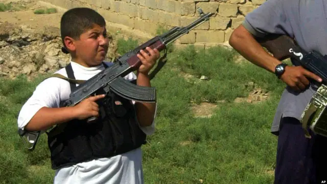 یک کودک در میان گروه های مسلح در فلوجه عراق، سپتامبر ۲۰۰۴.