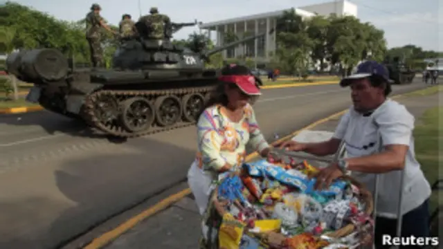 Vendedor ambulante en frente de un tanque