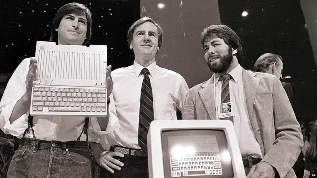 Jobs (esq.), Sculley (centro) e Wozniak posam com o computador pessoal Apple IIc