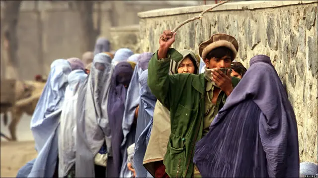 2001-жылы, декабрь. Чыбык кармаган афгандык Кабулдагы гуманитардык жардам үчүн кезекке турган аялдарды тартипке келтирүүдө.