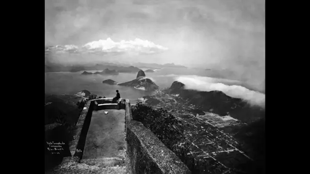 Do alto do mirante do Corcovado, o Rio como era em 1906, no mesmo ângulo que a estátua do Cristo veio a mirar a cidade depois de 1931. Segundo Sergio Burgi, coordenador da área de fotografia do Instituto Moreira Salles (IMS), a fotografia de Augusto Malta mostra como o morro já era usado como mirante no início do século. Nos terrenos abaixo, vê-se a área onde cresceria o bairro de Botafogo. (Foto: Augusto Malta/ Coleção Brascan Cem Anos no Brasil/ IMS) Do alto do mirante do Corcovado, o Rio como era em 1906, no mesmo ângulo que a estátua do Cristo veio a mirar a cidade depois de 1931. Segundo Sergio Burgi, coordenador da área de fotografia do Instituto Moreira Salles (IMS), a fotografia de Augusto Malta mostra como o morro já era usado como mirante no início do século. Nos terrenos abaixo, vê-se a área onde cresceria o bairro de Botafogo. (Foto: Augusto Malta/ Coleção Brascan Cem Anos no Brasil/ IMS)