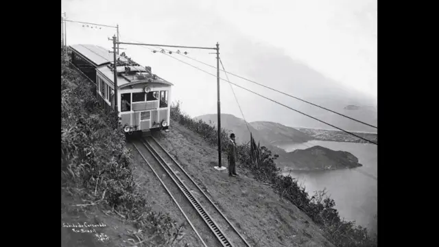 O bonde da Estrada de Ferro do Corcovado faz o percurso morro acima. Segundo Sergio Burgi, a via foi inaugurada no fim do século 19, ou seja, é bastante anterior ao Cristo. A fotografia de Augusto Malta não tem data, mas é atribuída à primeira década do século 20, quando o fotógrafo foi contratado pelo prefeito Pereira Passos para documentar as profundas mudanças urbanas que imprimiu à cidade, como a abertura da atual avenida Rio Branco. (Foto: Augusto Malta/ Coleção Brascan Cem Anos no Brasil/ Acervo Instituto Moreira Salles)
