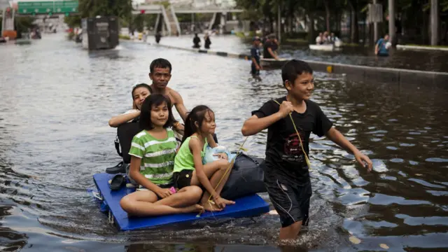 عائلة تفر بطريقتها الخاصة من المنطقة القريبة من النهر في أحد أحياء بانكوك