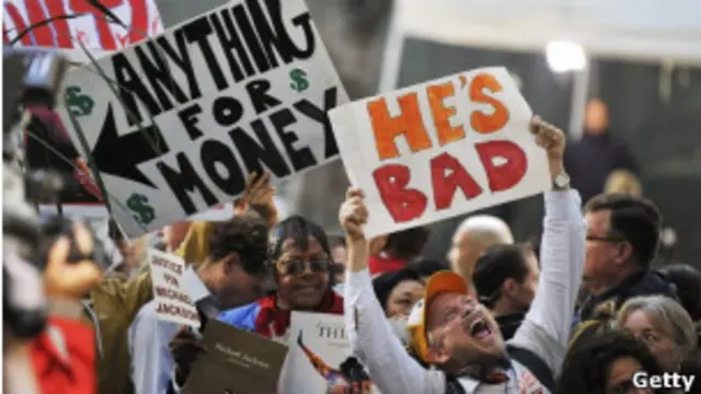 مخالفان دکتر موری در بیرون از دادگاه پلاکاردهایی در محکوم کردن او در دست دارند