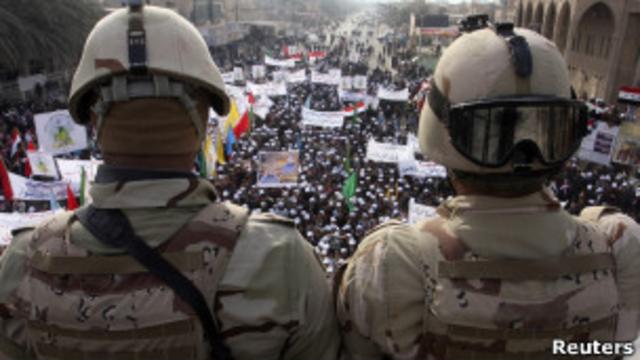 Manifestantes celebran la salida de las tropas estadounidenses de Irak ante la mirada del ejército iraquí.