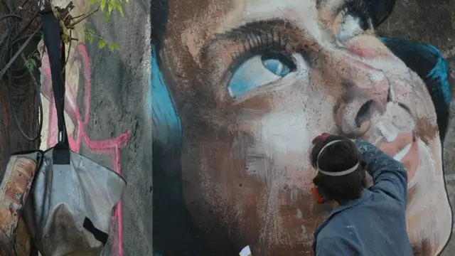 لومٹ اُس لڑکی کی تصویر سے مدد لیتے ہوئے اپنا شاہکار مکمل کر رہے ہیں۔ وہ انتہائی کم سامان کے ساتھ سفر کرتے ہیں۔ ان کے اوزار اور رنگ کی چند شیشیاں ایک چھوٹے سے بستے میں آ جاتی ہیں۔