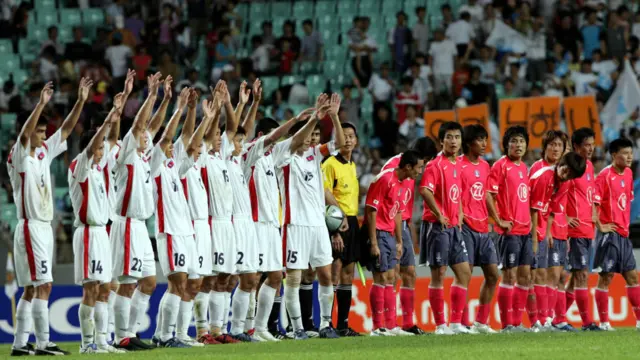 Thế giới bên ngoài thỉnh thoảng có dịp thấy người Bắc Hàn tại các sự kiện thể thao. Trên ảnh là các cầu thủ Bắc Hàn (mặc đồ trắng) vẫy tay chào người xem Nam Hàn, sau trận đấu tranh giải Vô địch bóng đá Đông Á, tại sân vận động Jeonju, tháng 8/2005. 
