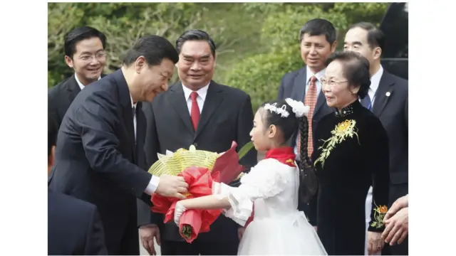 Ông Tập nhận hoa từ một học sinh khi Phó Chủ tịch Nguyễn Thị Doan và Thường trực Ban Bí thư Lê Hồng Anh đón ông ở Phủ Chủ tịch tại Hà Nội.