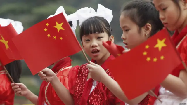 Các em bé Việt Nam cầm cờ hai nước đón ông Tập (hình của Reuters chụp trước Phủ Chủ tịch tại Hà Nội 21/12).