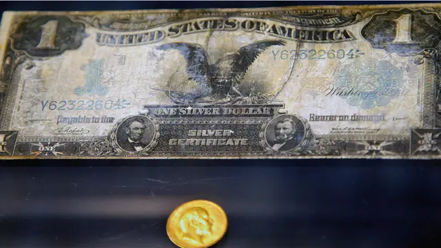 Un billete de dólar y una moneda de oro.