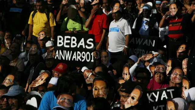 Lãnh đạo phe đối lập Malaysia, ông Anwar Ibrahim, đã được tòa xử trắng án, sau hai năm bị cáo buộc tội kê gian. Những người ủng hộ ông Anwar Ibrahim mang mặt nạ hình ông chờ đợi bên ngoài tòa án tại Kuala Lumpur.