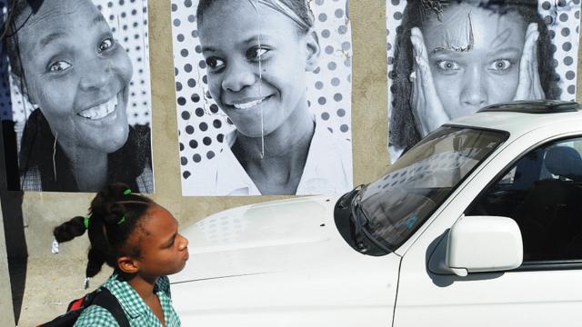 Estudiante pasa junto a afiches de haitianos