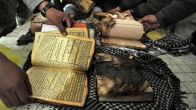 مظاہرین نے قرآن کے ادھ جلے نسخے اٹھا رکھے ہیں۔