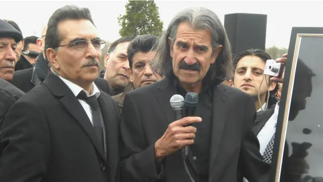منیر هویدا، در حال صحبت بر مزار برادرش