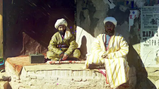 این دو مرد، بلیط برای سیرک می‌فروشند. در عکس، نوشته‌های روسی دیده می‌شوند که در آن زمان به تازگی در مناطق آسیای میانه باب شده بود. در نوشته‌های روی دیوار، تبلیغ مردان قوی و اسب سواران چابک و بی باک شده است
