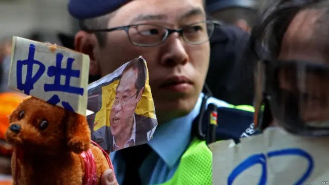 示威者手持身背候选人唐英年照片的玩具狗抗议。