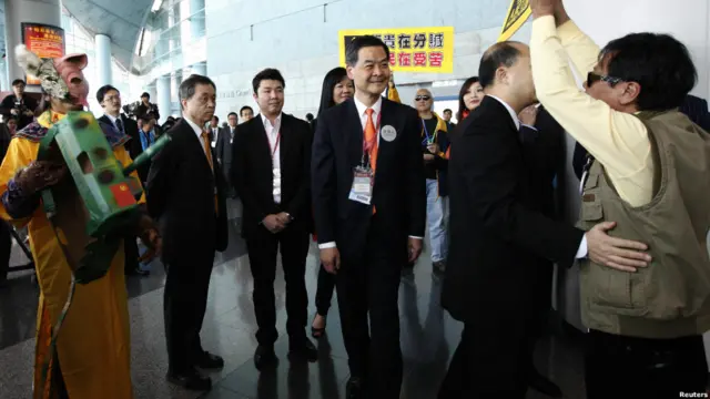 梁振英在示威者包围中步入投票中心。