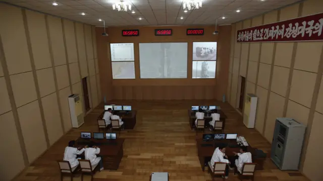 Phòng điều khiển của trung tâm vệ tinh Sohae. Biểu ngữ trên tường có nghĩa: "Phấn đấu xây dựng quốc gia hùng mạnh dựa trên sức mạnh công nghệ khoa học".