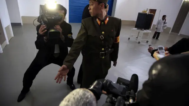 Lính gác Bắc Hàn vất vả giữ trật tự trong phòng họp ở trung tâm phóng vệ tinh, khi các nhà báo nước ngoài hăm hở kéo vào chụp ảnh.