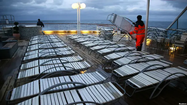 夜幕降临，船上工作人员在清理甲板上的躺椅。乘客将于周日（4月15日）格林尼治时间凌晨2点20在北大西洋的出事地点举行一个纪念仪式，来缅怀当年沉船的情景。 