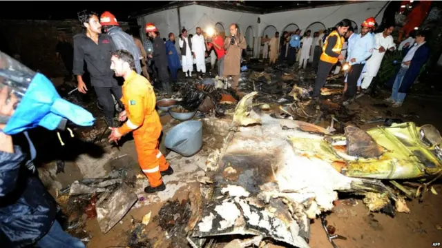 Petugas penyelamat mencari korban di tengah rongsokan badan pesawat yang menurut saksi mata menabrak rumah penduduk.