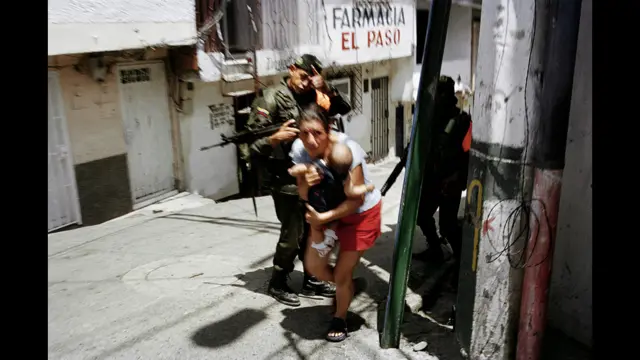 Mujer y niño huyen de un enfrentamiento entre las FARC y el ejército colombiano. Comuna 13, Medellín, octubre 2002. Foto: Stephen Ferry