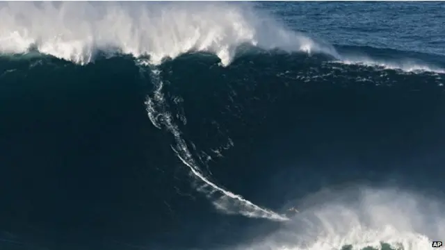 Tubuh Garret McNamara terlihat kerdil yang dikelilingi oleh dinding air raksasa.