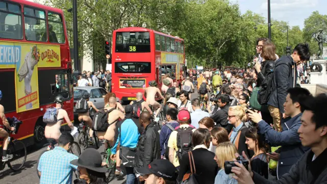 围观群众蜂拥道路两侧，甚至各展其能，占据有利制高点。