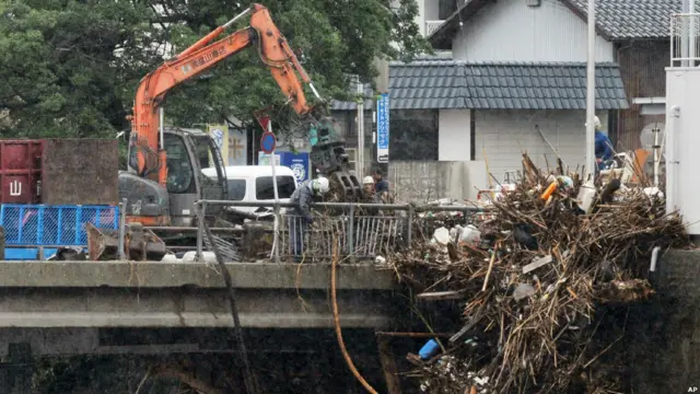 Traktor membersihkan puing-puing banjir