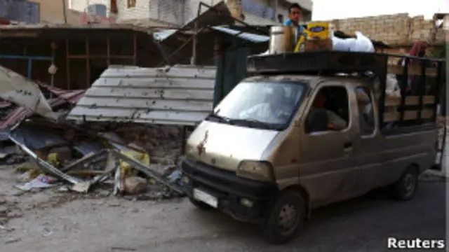 Người tị nạn Syria lái xe qua đống đổ nát do giao tranh