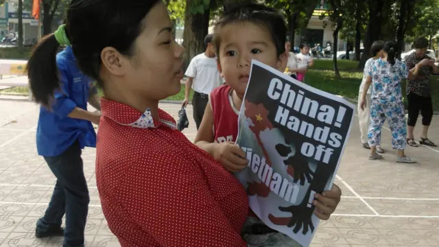 Một người mẹ trẻ ẵm con nhỏ tham gia vào đoàn tuần hành