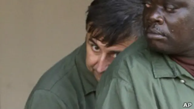 Александр Фишенко прячет лицо за плечом другого заключенного