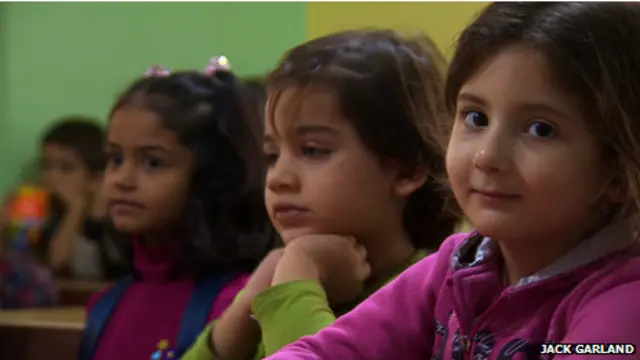 Una niña sonríe a la cámara mientras atiende a sus clases en sirio, en Turquía.