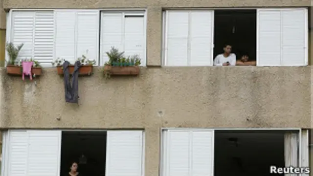 Закрытые ставнями окна и люди, выглядывающие на улицу