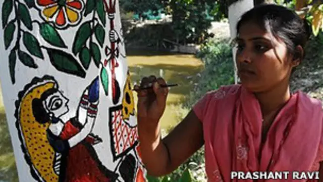 Una artista dibuja una deidad hindú sobre un árbol con la técnica Madhubani
