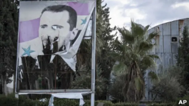 Рекламный щит с изорванным плакатом Башара Асада