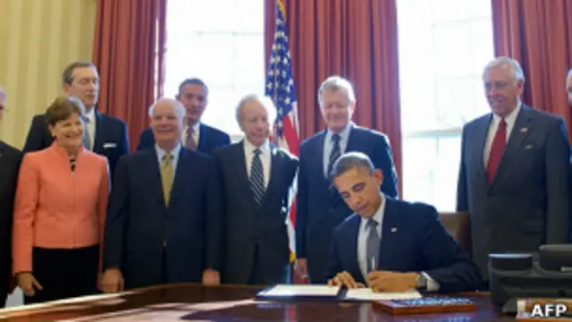 Барак Обама подписывает закон в окружении членов администрации