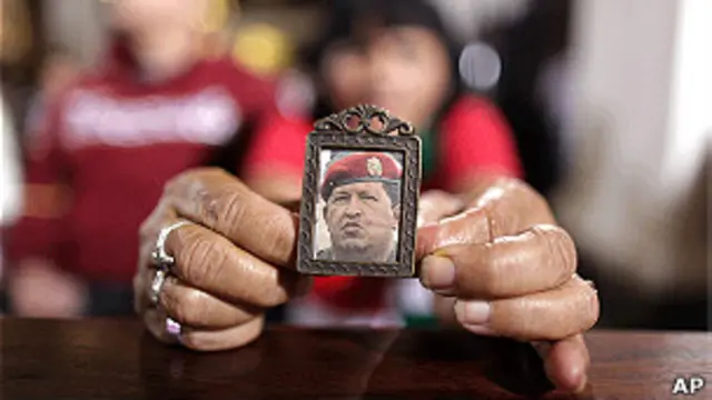 Mujer sostiene un pequeño retrato de Chávez con sus manos.