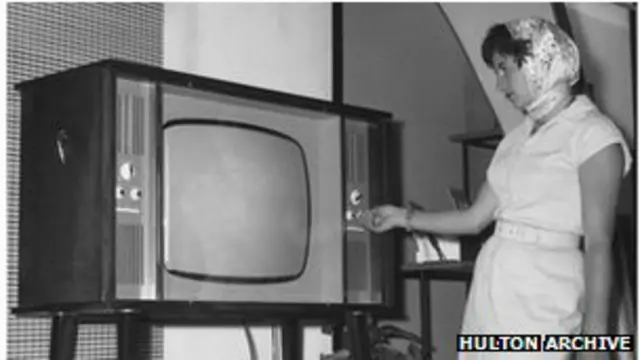 Mujer enciende aparato de TV (foto de archivo)