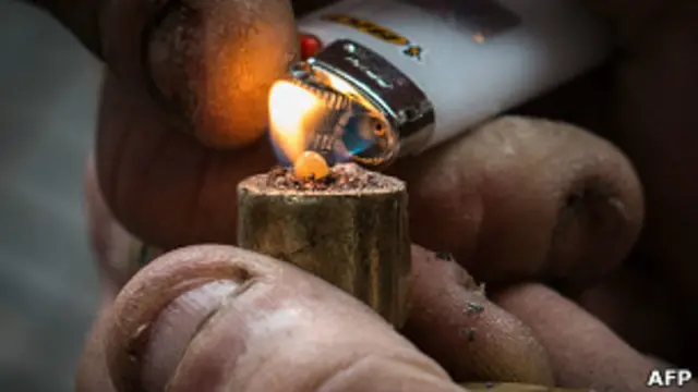 Наркоман разжигает трубку с наркотиком