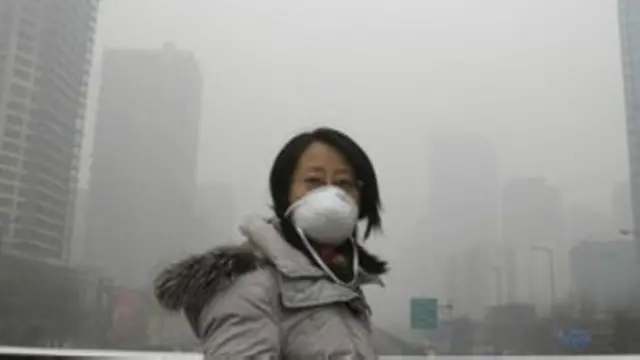 बीजिंग में प्रदूषण वाले कोहरे की वजह से लोग चेहरे पर मास्क लगाकर घूमते हैं.