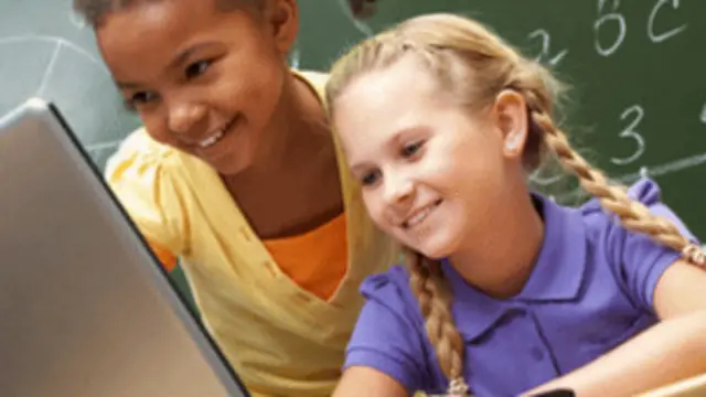 Dos niñas usan una computadora