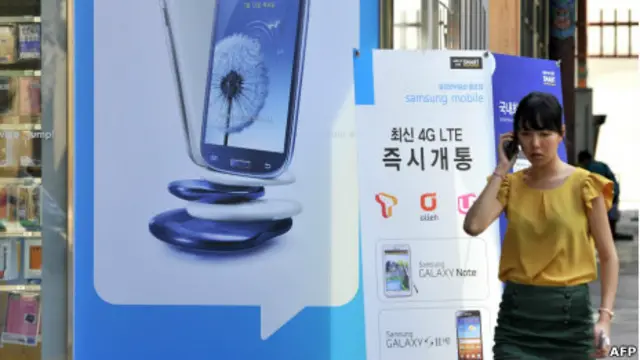 Mujer hablando frente a anuncio de Samsung, el gigante surcoreano que ya le pisa los talones a Apple