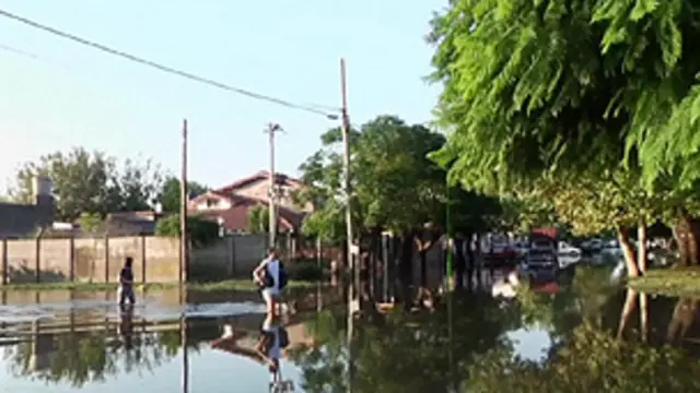 Moradores tentam atravessar área inundada na Argentina (BBC)