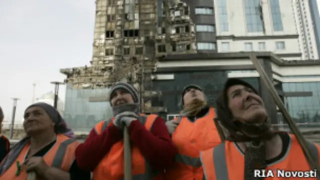 Рабочие у сгоревшего комплекса в Грозном