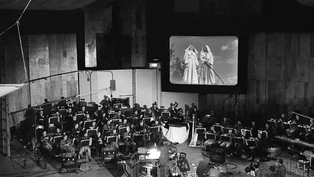 گروه ارکستر در کنار پرده فیلم در حال ضبط موسیقی 