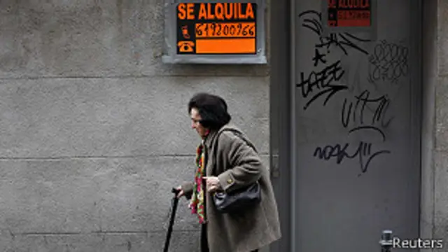 Mujer camina frente a una tienda cerrada a raiz de la crisis