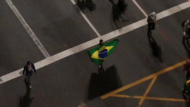 No início dos protestos de segunda-feira, um manifestante abre a bandeira do Brasil na avenida Paulista. Foto: Nelson Garcia Perandréa