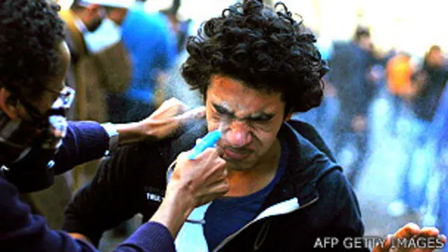 Un manifestante intenta lavar el gas lacrimógeno de los ojos de otro manifestante en Egipto