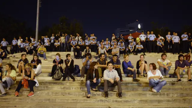 Onu izlemek isteyenler de Gezi Parkı'nın merdivenlerine yerleşti. Polisler uzun süre arka planda bekledi.
